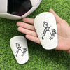 A hand holds a white mini mouse featuring a stick figure drawing of a soccer player on green grass with a soccer ball and a s