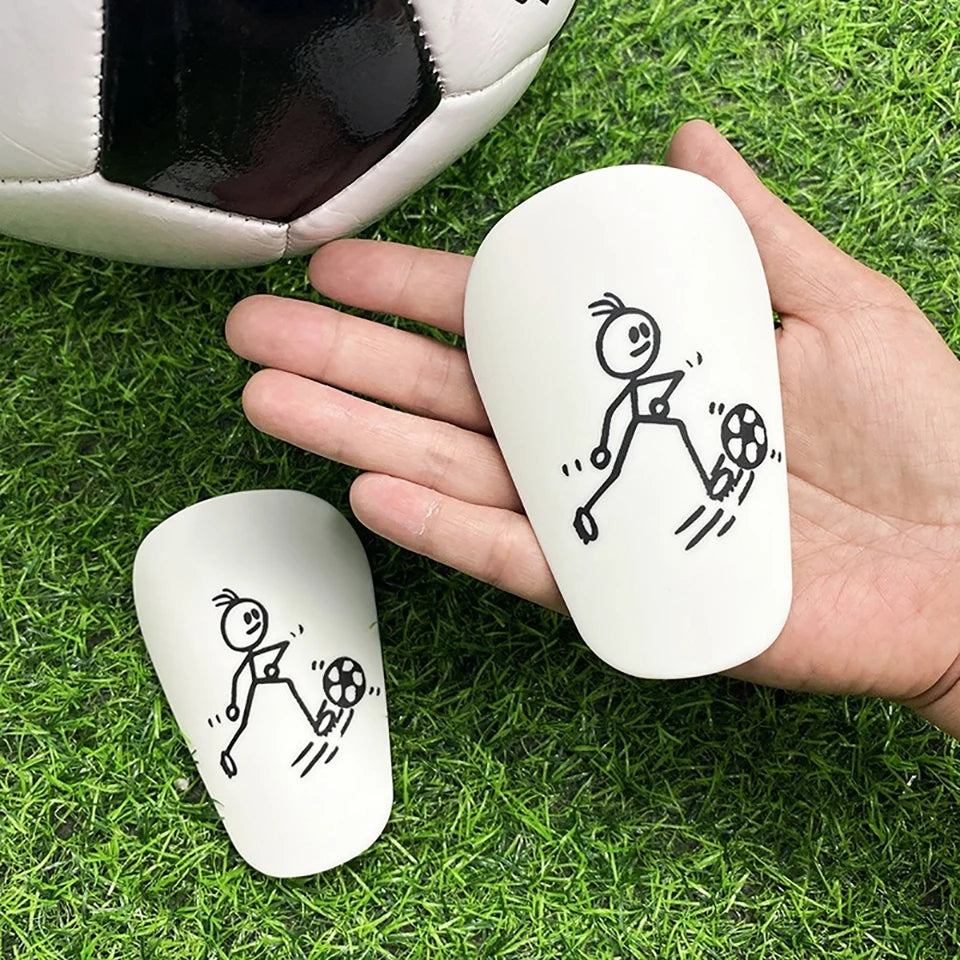 A hand holds a white mini mouse featuring a stick figure drawing of a soccer player on green grass with a soccer ball and a s