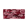 A close-up of a deep red fabric featuring an intricate white bohemian vintage print pattern.