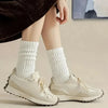 Primer plano de las piernas de una persona vistiendo calcetines de punto blancos hasta media pantorrilla y zapatillas de lona