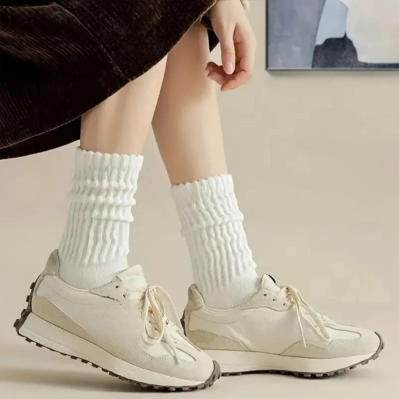 Primer plano de las piernas de una persona vistiendo calcetines de punto blancos hasta media pantorrilla y zapatillas de lona