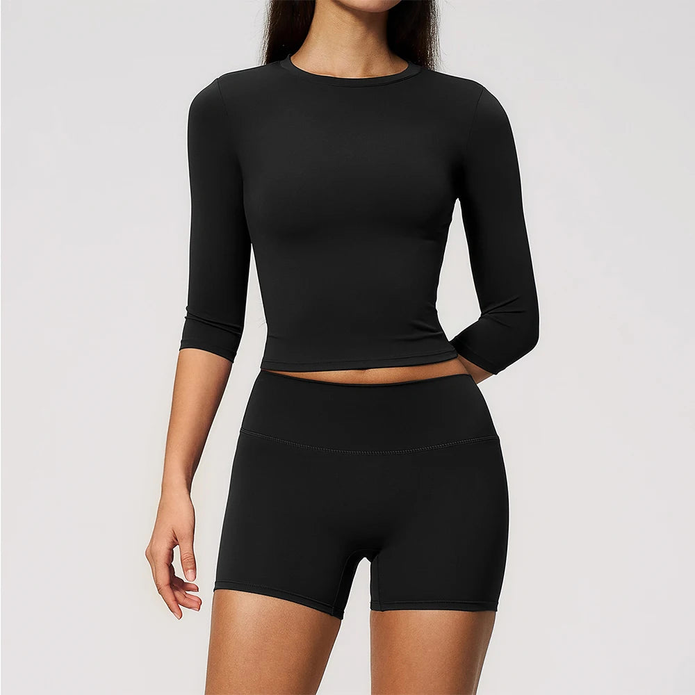 A woman wearing a black long-sleeved top and matching black yoga leggings set.