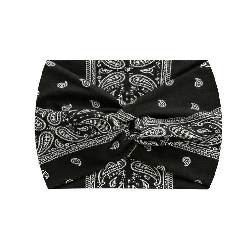 Black fabric with white paisley print tied into a wide knotted headband