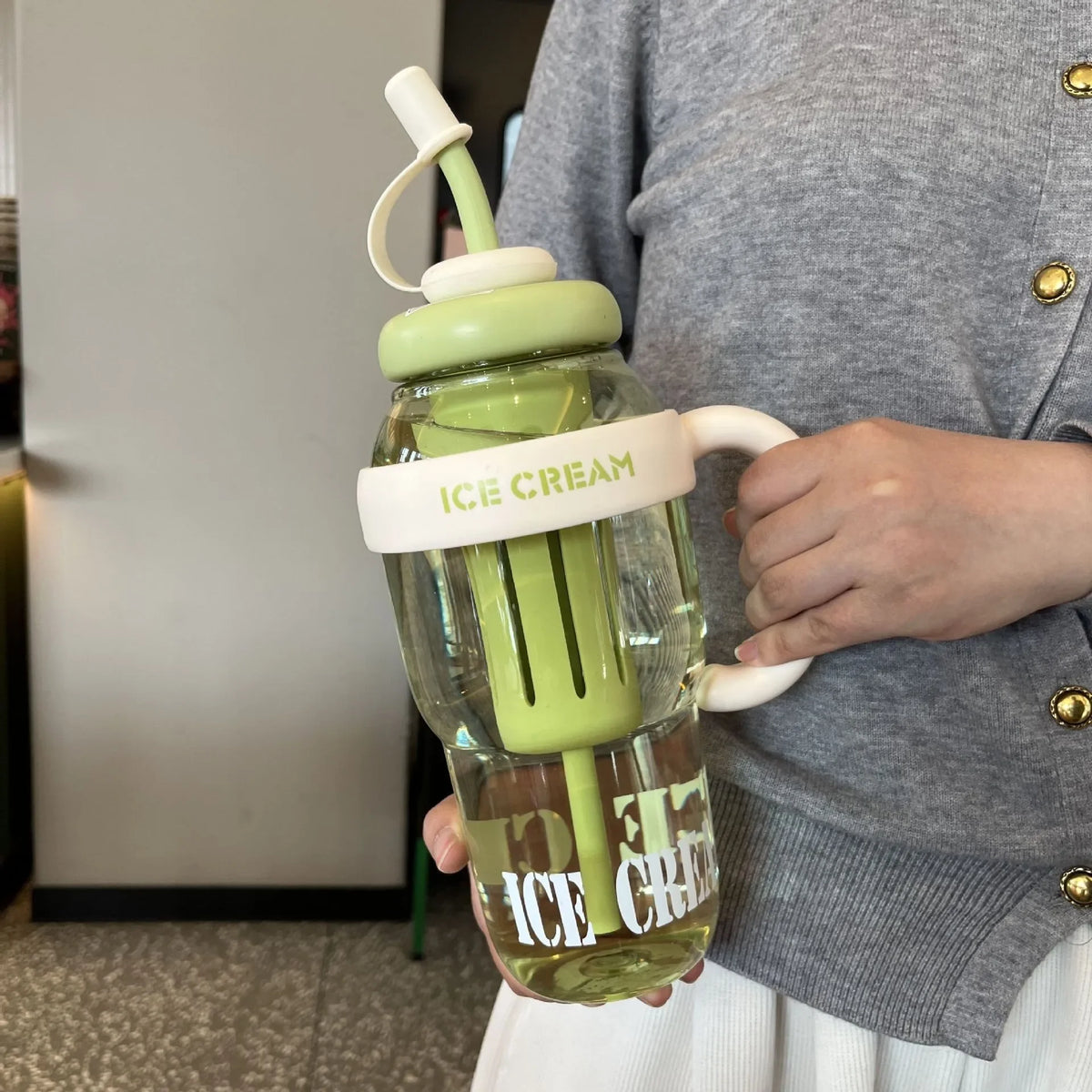 A person holds a large capacity portable plastic drinking cup filled with iced tea or lemonade.