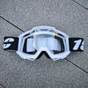Lunettes de moto tout-terrain et ATV blanches avec sangle noire posées sur une surface grise.
