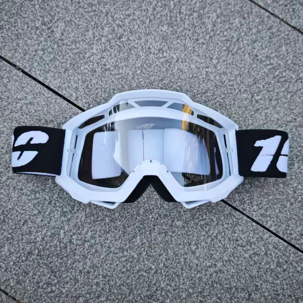 Lunettes de moto tout-terrain et ATV blanches avec sangle noire posées sur une surface grise.