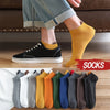 Ein Paar senfgelber Knöchelsocken, getragen mit blauen Jeans und schwarzen Canvas-Schuhen.