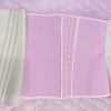 A double compression waist trainer corset body shaper in pink and cream colors displayed on a quilted surface.