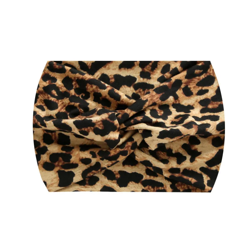 A close-up of a brown and black leopard print fabric tied into a wide, knotted headband.