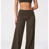 A woman models olive green flared high-waist yoga pants and a matching sports bra top.