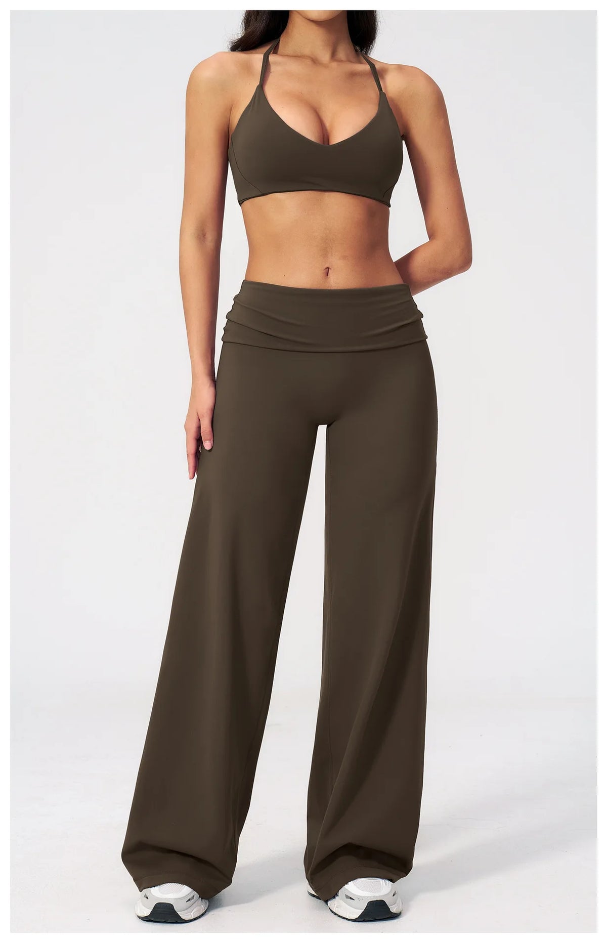 A woman models olive green flared high-waist yoga pants and a matching sports bra top.