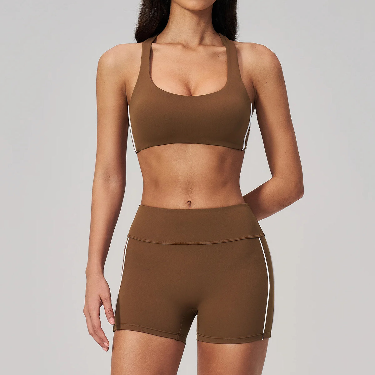 A woman models a two-piece brown yoga and sports tracksuit set consisting of a cropped top and matching shorts.
