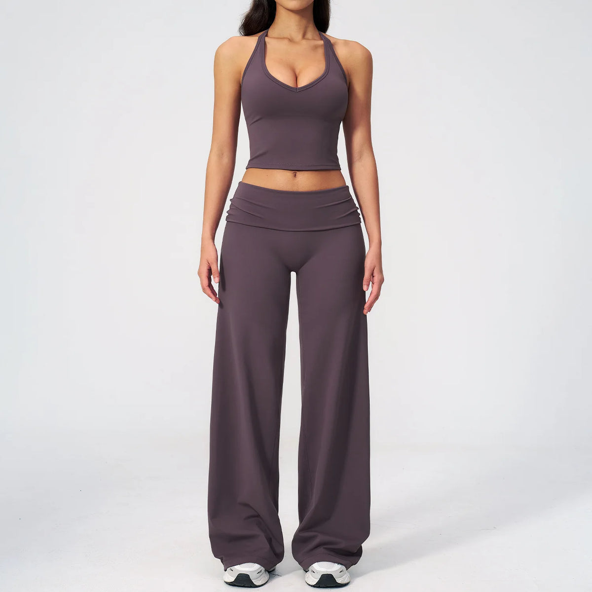 A woman wearing a dark purple women's premium fitness tracksuit top and matching pants.