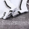 A pair of white and gray color-block mesh ankle socks lying on a dark surface.