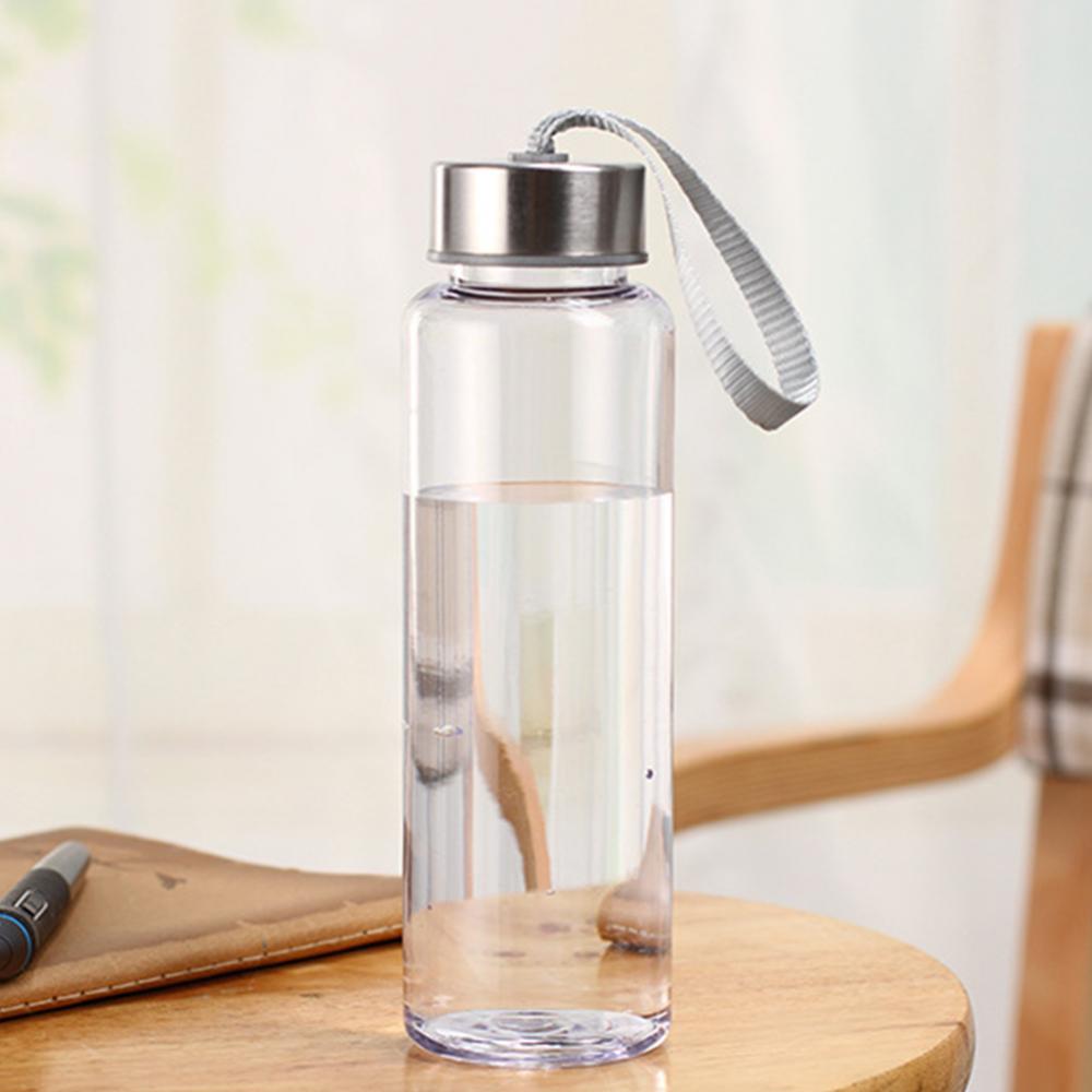 Une bouteille d'eau de sport en plastique transparent avec un bouchon argenté, posée sur une surface en bois.