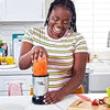 Una mujer usa un set de licuadora de 11 piezas Magic Bullet para mezclar ingredientes en una cocina.