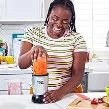 Una mujer usa un set de licuadora de 11 piezas Magic Bullet para mezclar ingredientes en una cocina.