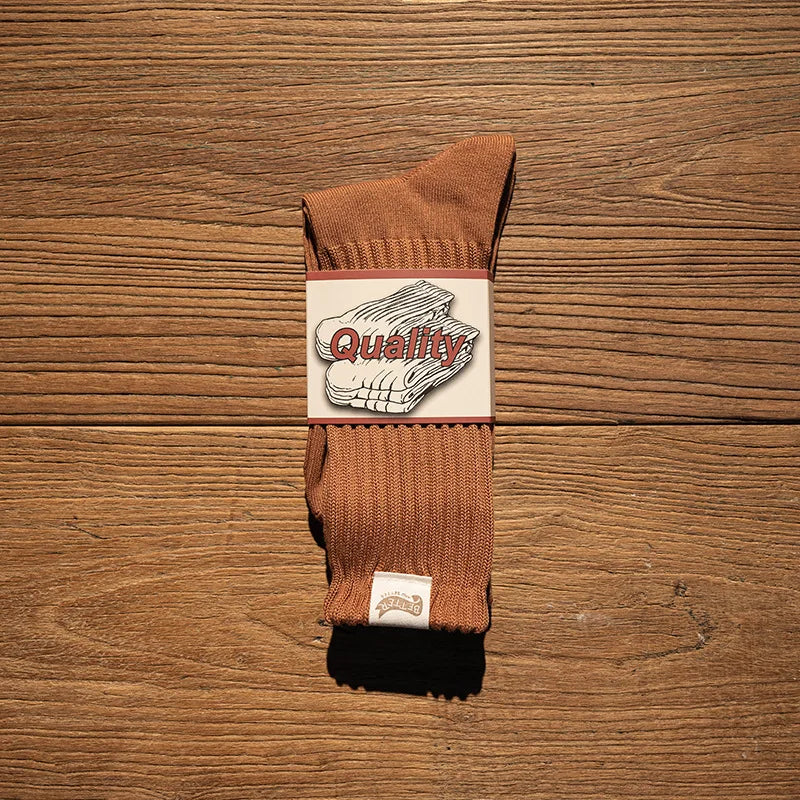 A pair of brown thick cotton tube socks with a white label featuring the word Quality