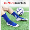 A pair of blue and gray athletic soccer socks lying on green grass next to a soccer ball.