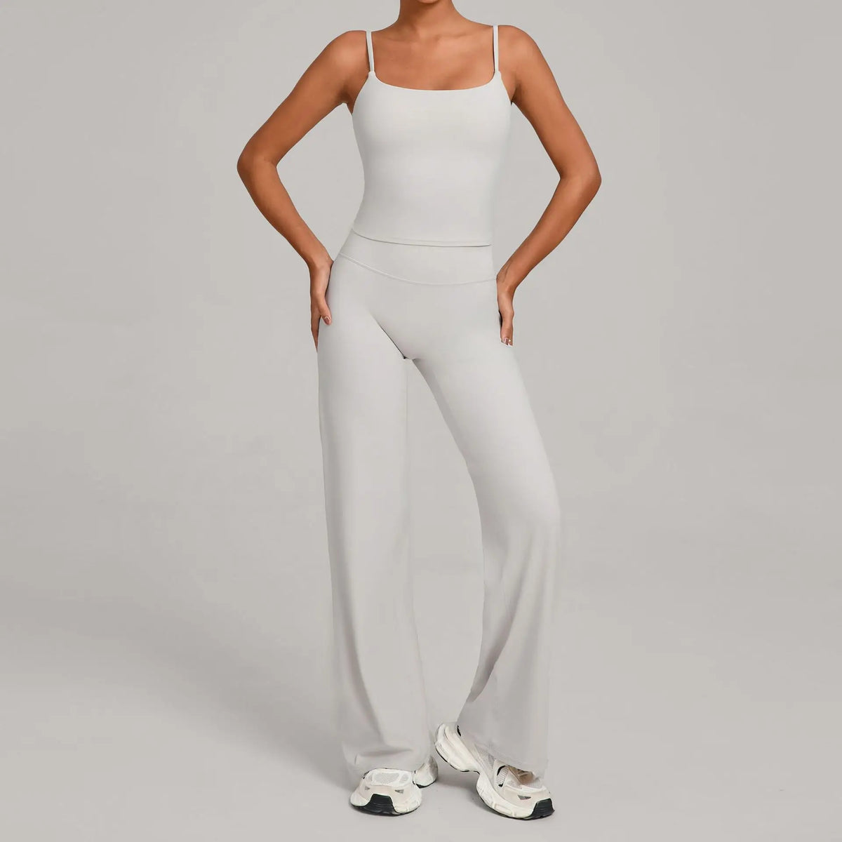 A woman models a light gray high-waist yoga and fitness tracksuit set consisting of a cropped top and matching full-length pa