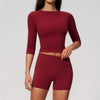 A woman wearing a long-sleeved maroon yoga top and matching high-waisted leggings set.