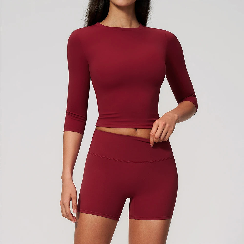 A woman wearing a long-sleeved maroon yoga top and matching high-waisted leggings set.