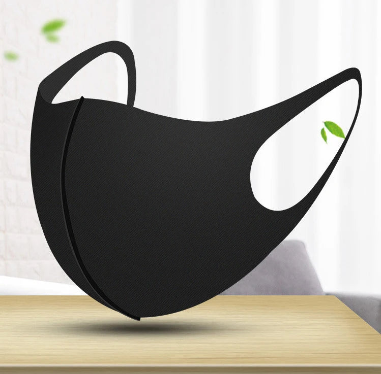Black UV protection face mask hanging on a wooden table.
