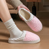 A pair of pink and white plush fleece slippers being held, showing the interior lining and exterior texture.