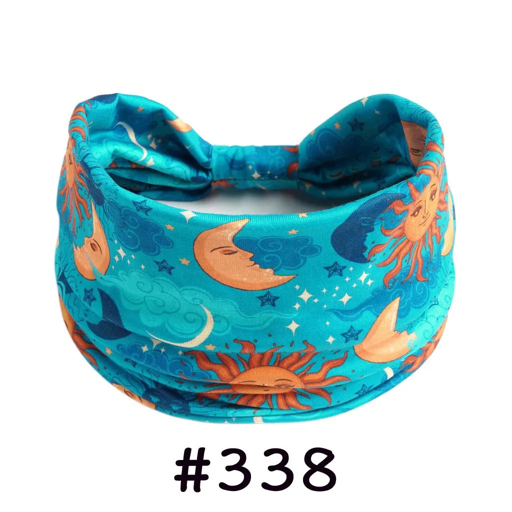 A teal fabric headband with a floral and moon design, suitable for yoga or workout.