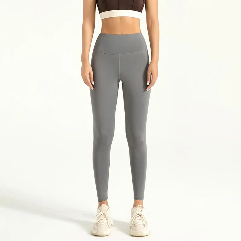 A woman wearing seamless gray high-waist yoga leggings and a cropped top, standing full length.