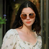 A woman wearing round, rose gold-framed sunglasses outdoors.