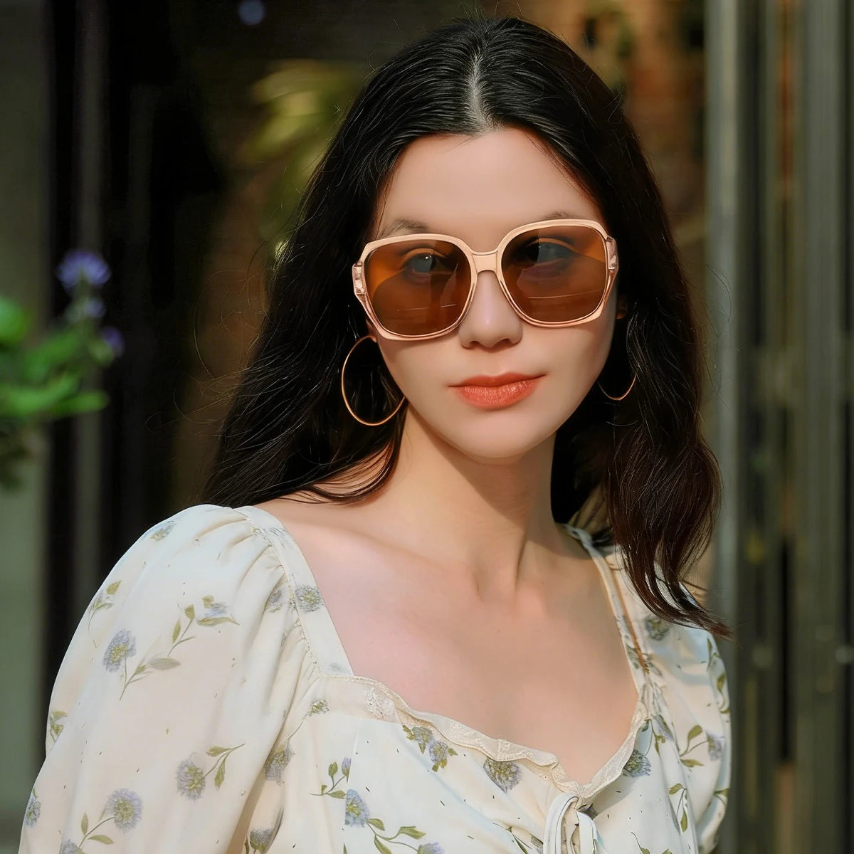 A woman wearing round, rose gold-framed sunglasses outdoors.