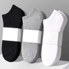 Tres pares de calcetines de algodón transpirables para el tobillo en negro, gris y blanco mostrados uno al lado del otro.