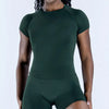 A woman wearing a dark green seamless high-waist yoga set top and bottoms.