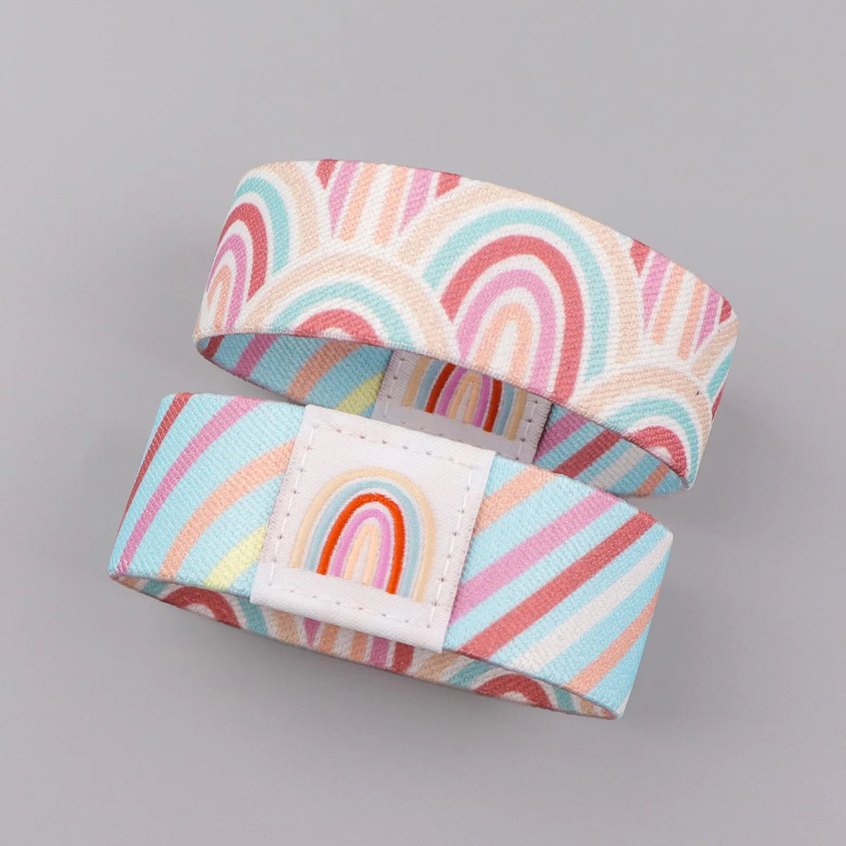 A pink and white striped silicone wristband bracelet featuring a rainbow pattern.