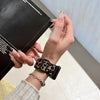 A hand wearing a leopard print silicone watch band on a wrist, holding a black box.