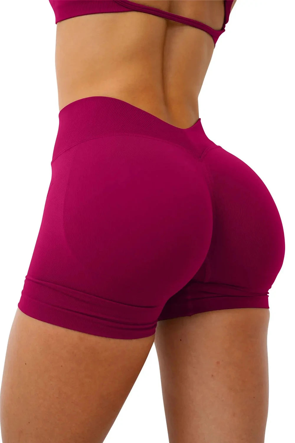 A woman wearing seamless magenta yoga shorts during a workout.