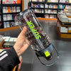 A hand holds a clear insulated sports water bottle with a leakproof straw, featuring green lettering.