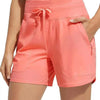 A model wears coral pink high-waisted quick-dry athletic shorts with a drawstring waist.