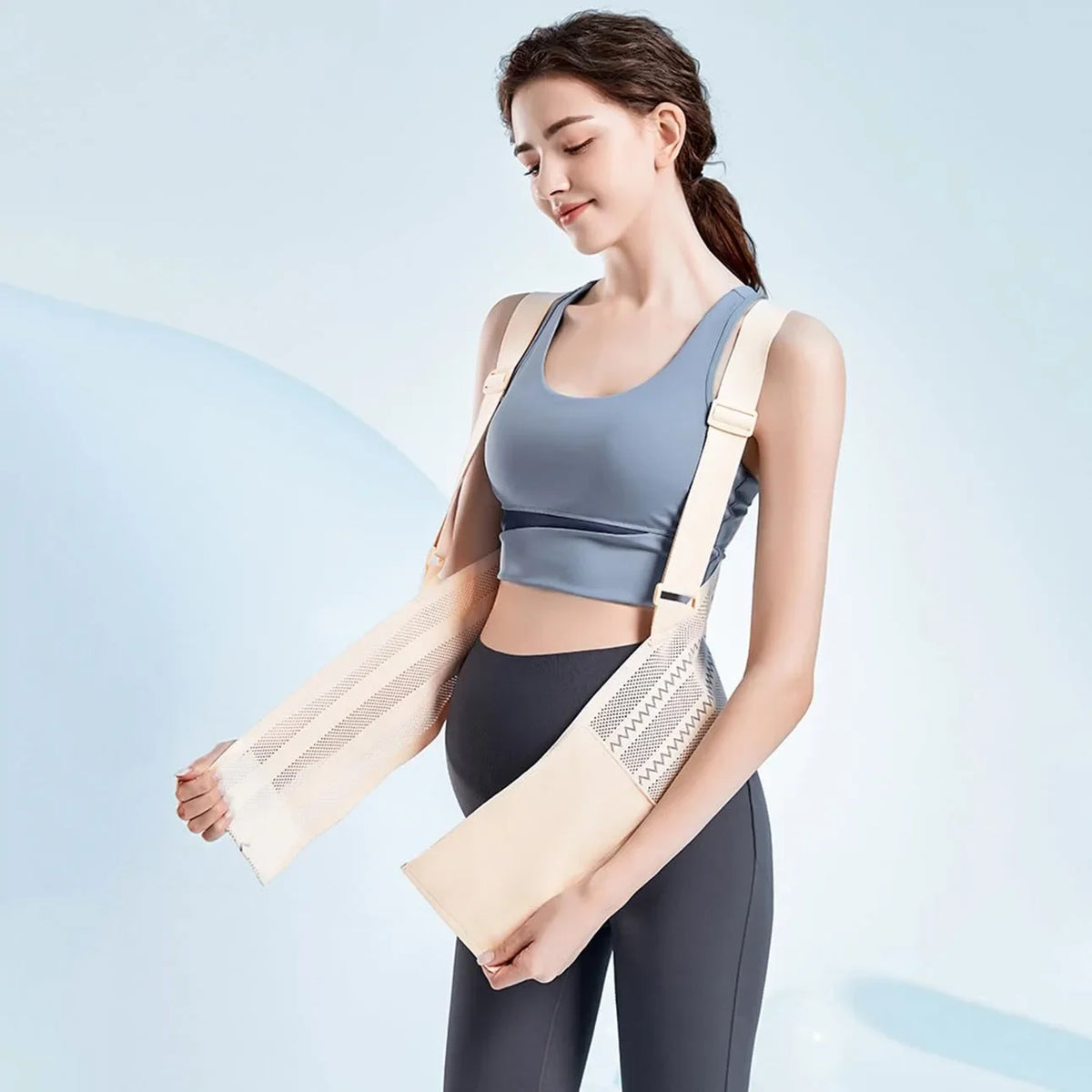 Une femme portant un soutien-gorge abdominal beige clair sur un haut gris et des leggings foncés.