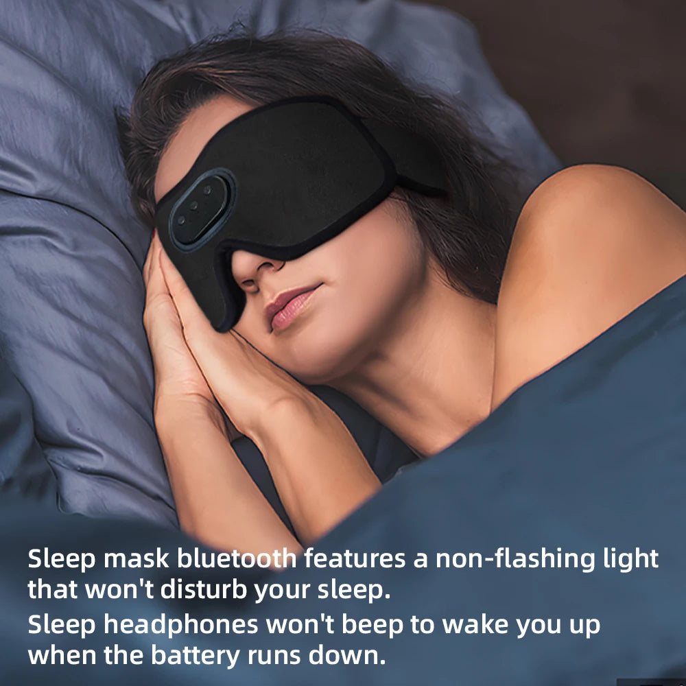 A woman is resting her head on a pillow while wearing a black sleep mask and headphones.