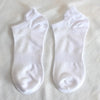 Ein Paar weiße Socken liegen flach auf einer weißen Oberfläche.