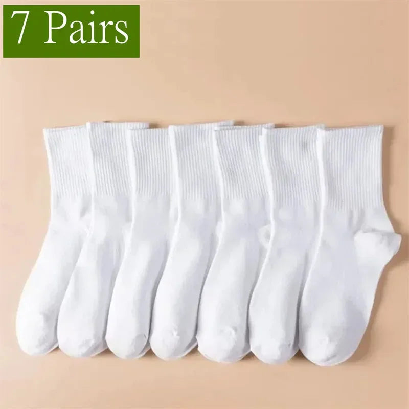Un ensemble de sept paires de chaussettes de sport blanches, à mi-mollet et respirantes, posées sur un fond clair.