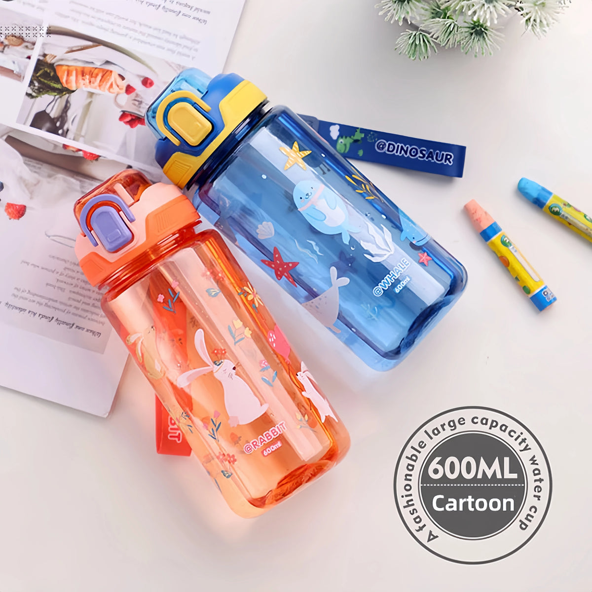 A clear blue dinosaur silicone straw water bottle with a yellow cap and a pink orange bottle nearby.