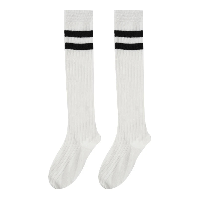A pair of white cotton knee high socks with black horizontal stripes.