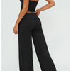A woman models black flared high-waist yoga pants with a fitted crop top, shown from the back.