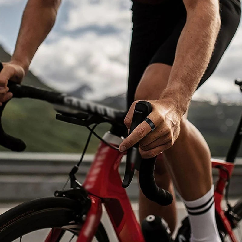A person is riding a red bicycle while holding a black fitness tracker on the handlebars.