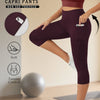Model trägt hochdehnbare, nicht durchsichtige, maroonfarbene Caprihosen mit Taschen und einem Sportball.