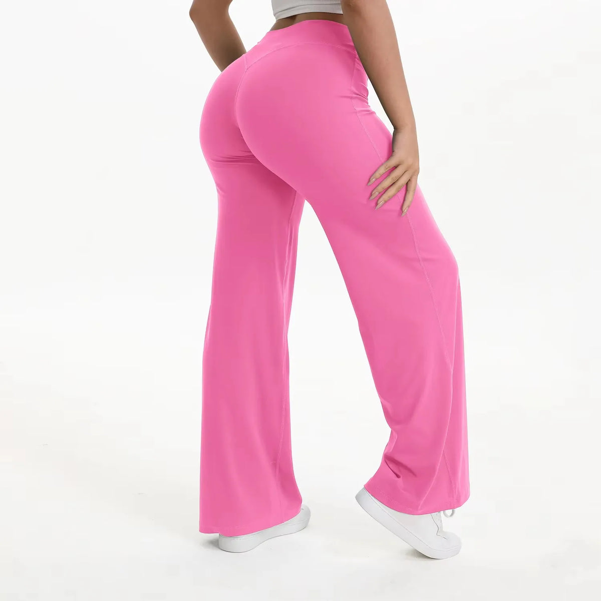 A woman is modeling bright pink high-waist yoga pants in a full-length shot.