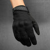 Gant tactique noir porté à la main, montrant le matériau texturé et la sangle de poignet.